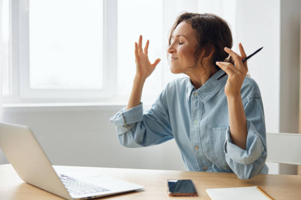 istock Furious angry evil beautiful curly businesswoman hates computer crash having problem with broken laptop swings at gadget raises hands up sitting at home office. Freelancer work concept. Copy space 2149013214