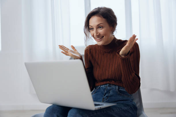 istock woman working on the computer, online communication, webinars, smiling and happily spreading her hands. trading, investing. 2149013810