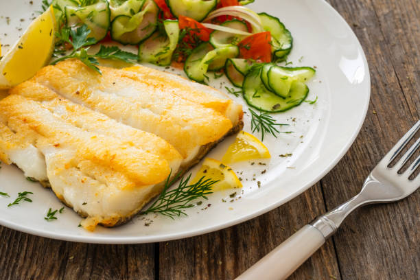 istock Fried halibut fillet and fresh vegetables on wooden table 2149015040
