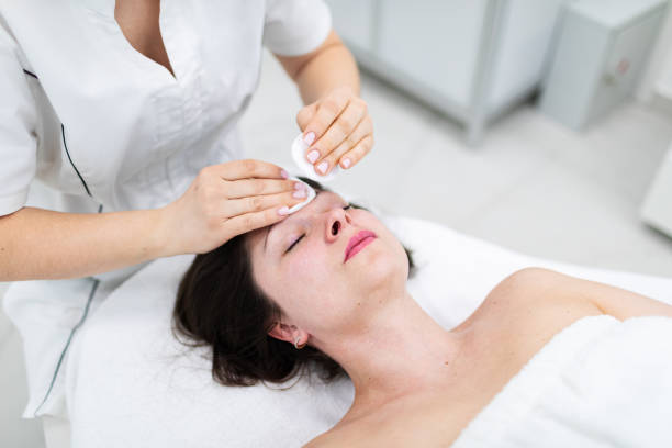 istock Cosmetologist cleaning patient face with cleanser before making beauty procedure 2149015320