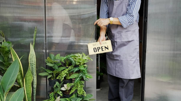 istock Cafe owner hanging open sign on door 2149016363