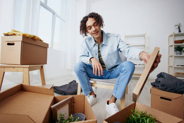 istock guy with curly hair unpacking things from boxes in the room Lifestyle 2149018237