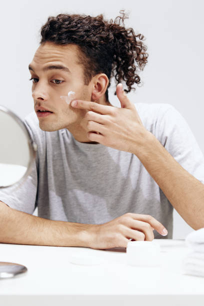 istock handsome guy applying cream on the face and looking in the mirror cosmetology Lifestyle 2149019321