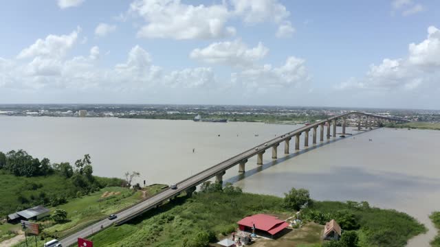 Wide angle aerial shot of Jules Wijdenbosch Bridge between Paramaribo and Meerzorg in Suriname, South America, with traffic as drone orbits around bridge