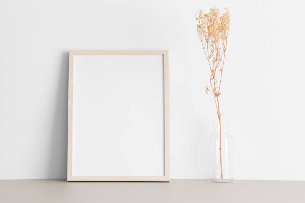 istock Wooden frame mockup with a gypsophila decoration on the beige table. 2149021489