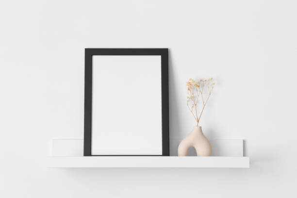 istock Black frame mockup with a gypsophila decoration on the wall shelf. 2149021497