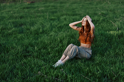 Portrait of pretty young Caucasian woman crouching in grass.