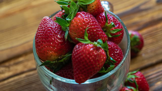Red ripe strawberries in a cup rotating on a wooden table. Juicy Fresh Ripe Scarlet Red Strawberries, Summer Useful Berries. The Concept Of The Right To Natural Healthy Food.