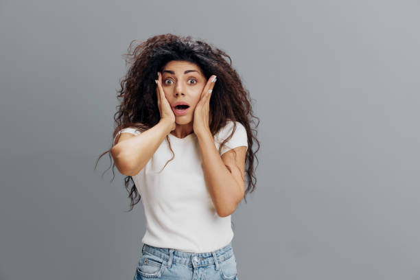istock Curly Latin Female feeling scared, shouting in panic on gray studio background. Terrified young woman with afro suffering from phobia, being scared or frightened. Negative human emotions concept 2149025256