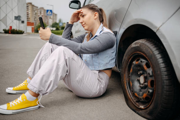 istock Woman having flat tyre and using mobile phone to ask for help 2149025398