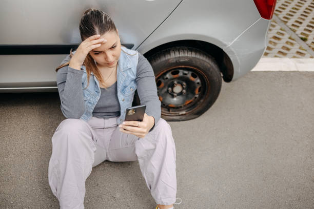 Woman having flat tyre and using mobile phone to ask for help