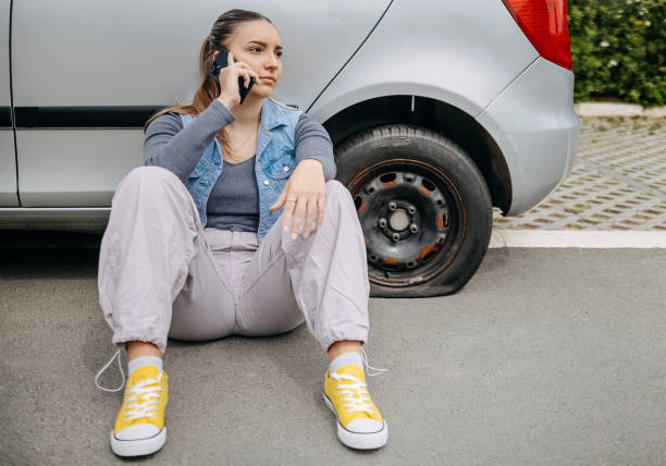 istock Woman having flat tyre and using mobile phone to ask for help 2149025413