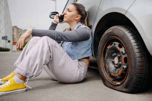 istock Woman having flat tyre and using mobile phone to ask for help 2149025426
