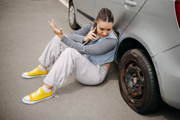 istock Woman having flat tyre and using mobile phone to ask for help 2149025427