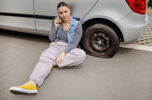 istock Woman having flat tyre and using mobile phone to ask for help 2149025432