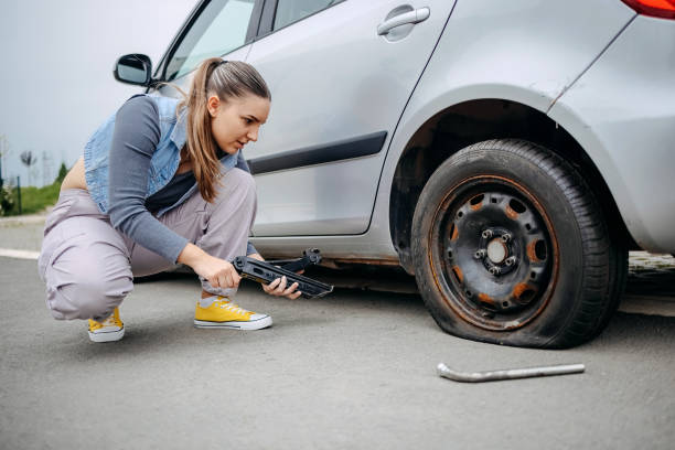 istock Woman changing flat tyre on her car using car jack 2149025471