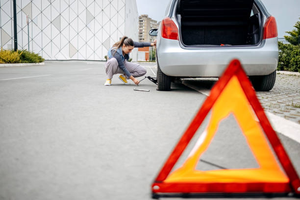 istock Woman changing flat tyre on her car using car jack 2149025473