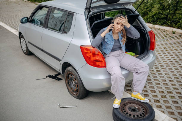 istock Woman sitting on back of her car asking for support using mobile phone because having a flat tyre 2149025496
