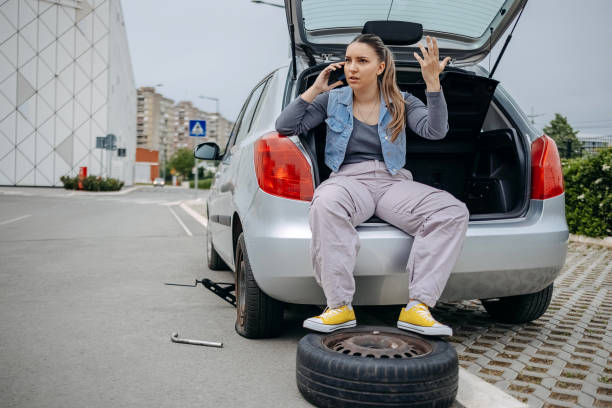 istock Woman sitting on back of her car asking for support using mobile phone because having a flat tyre 2149025498