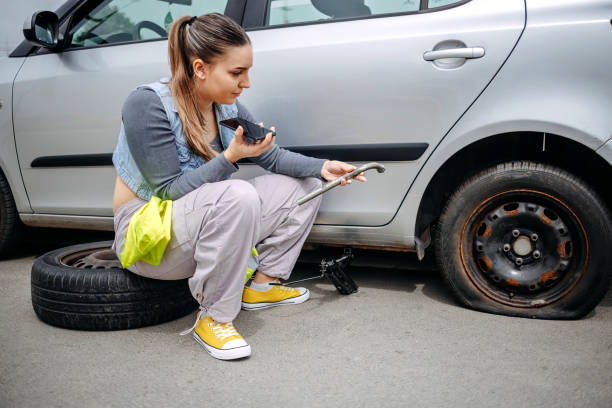 istock Woman changing flat tyre on her car having assistance on mobile phone speaker 2149025574