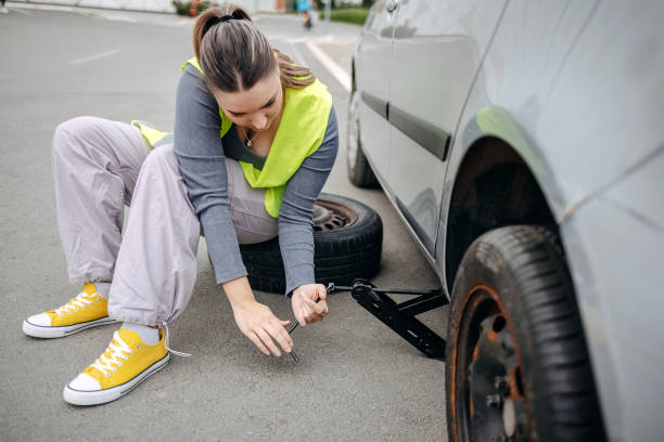 istock Woman changing flat tyre on her car using car jack 2149025633