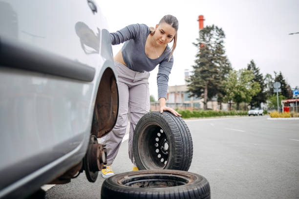 istock Woman changing flat tyre on her car 2149025721