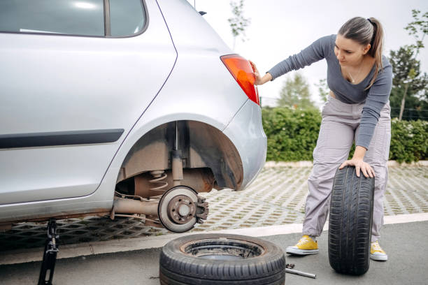 istock Woman changing flat tyre on her car 2149025734