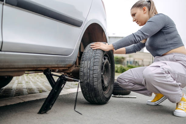 istock Woman changing flat tyre on her car 2149025765
