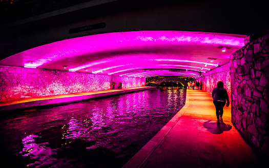 San Antonio, Texas, USA - People walk on Riverwalk under a iluuminated bridge.