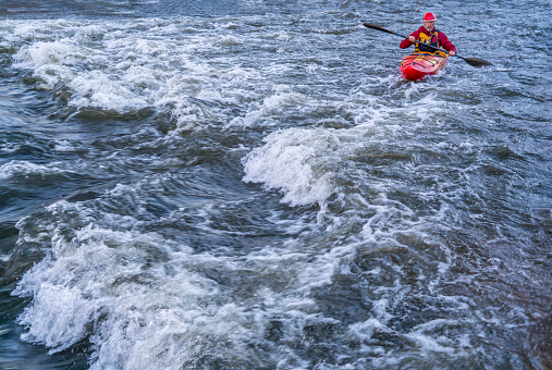 whitewater kayaker paddling upstream the river rapid