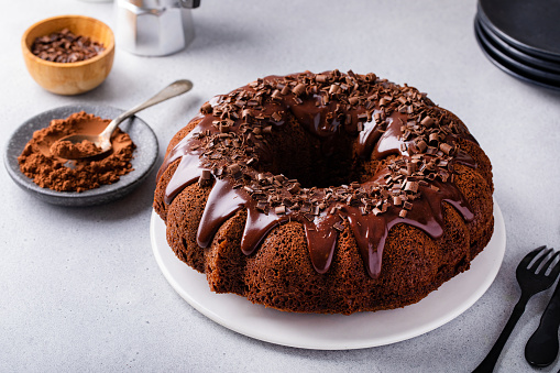 Chocolate bundt cake with chocolate ganache on top on white table