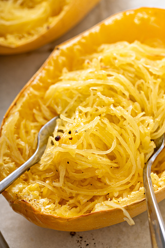 Spaghetti squash baked and pulled apart with two forks, ready to eat on a baking pan