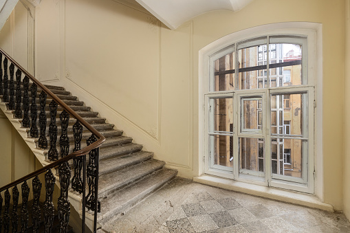 Interior view of a historic staircase with wrought iron railings and an antique window.