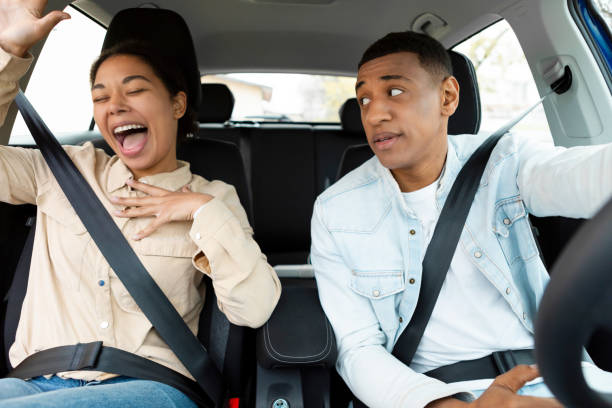 istock Joyful woman singing while sitting in car while her husband looking at her and driving automobile 2149032366