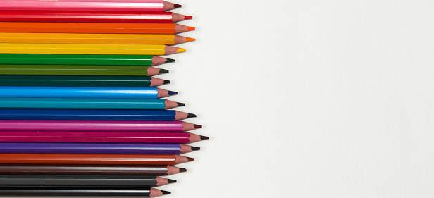 Background, waves of bright coloured pencils isolated on a white background