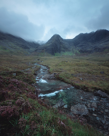 A winding river leading to cloud-covered mountain peaks. Scenic summer landscape with river in the morning. Fairy Pools, Isle of Skye, Scottish Highlands, UK