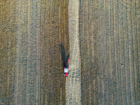 A farmer on a tractor plowing land in a private field in the village area.