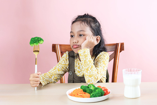 Asian Little Cute Girl Refuses to Eat Broccoli Healthy Vegetables. Picky Eater Kids Concept