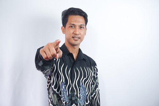 Young handsome man wearing batik shirt over white background pointing to you and the camera with fingers, smiling positive and cheerful