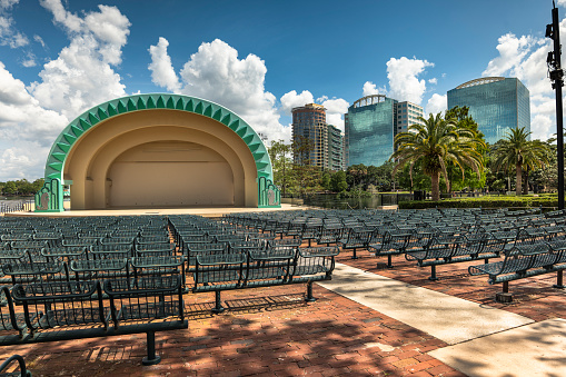 Orlando, Florida - April 7, 2023:  Urban downtown skyline and amphitheater bandshell in Lake Eola park on the water in the city centre of Orlando Florida