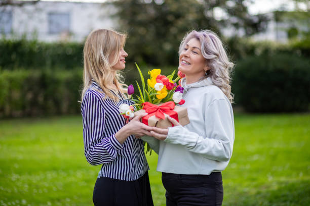 istock Mother and daughter smiling with gift and tulips. 2149036645