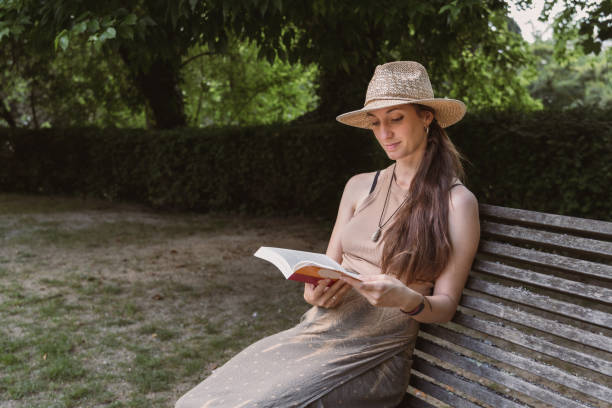 istock natural woman in hat reading a book in nice sunny green natural environment 2149036708