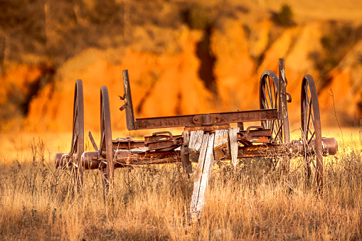 Antique wagon sitting in a field with Red Bluff background