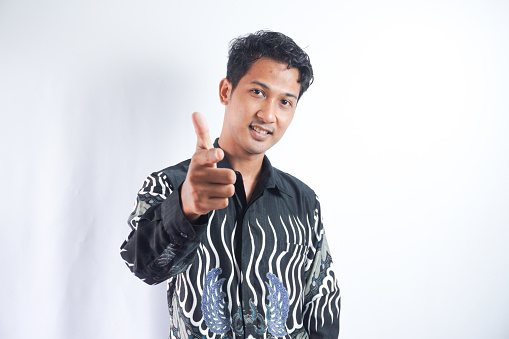 Young handsome man wearing batik shirt over white background pointing to you and the camera with fingers, smiling positive and cheerful