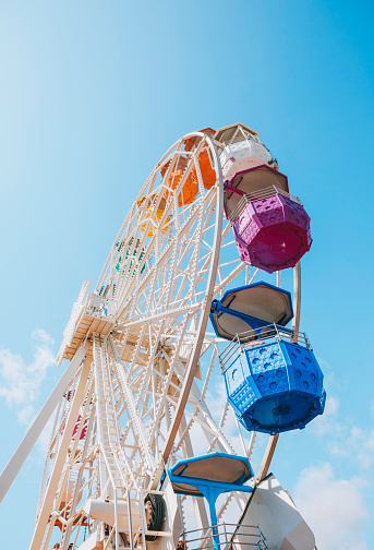 White Ferris wheel turning with colourful baskets against clean sunny blue sky background on sunny day in at Tibidabo, Barcelona