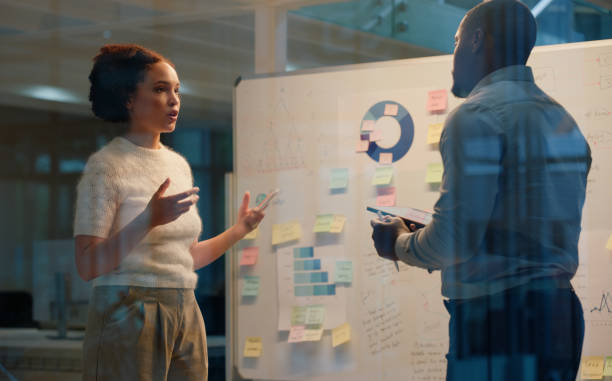 istock Man, woman and notes on whiteboard for project management, planning and strategy in office. Event manager, man and meeting in workplace for communication, logistics and schedule with business budget 2149038047