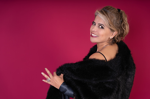 A woman wearing a black fur coat striking a pose for a picture.