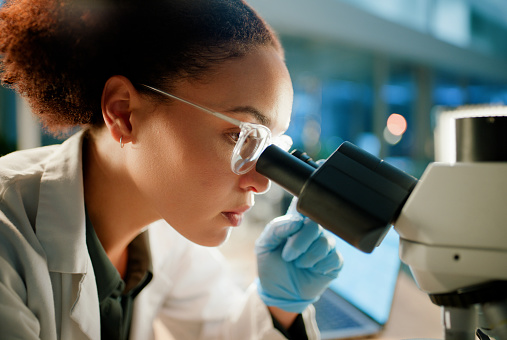 Scientist, microscope and analysis in lab for medical study, innovation and stem cell research. Woman, experiment and investigation with biotechnology for dna, examination or test for bacteria