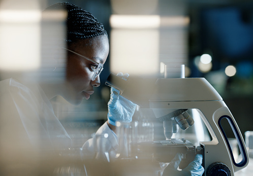 Scientist, microscope and analysis in lab for healthcare, innovation and development in stem cell research. Black woman, investigation and experiment with biotech for dna, exam or test for bacteria