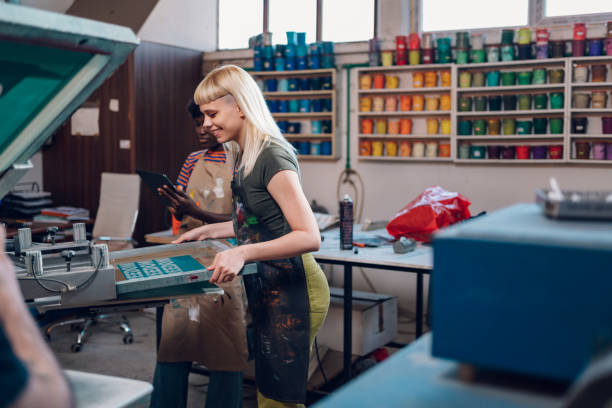 istock Print shop worker putting plate on press and interracial expert watching 2149040872
